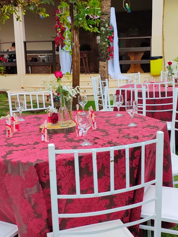 Mesas com toalhas vermelhas e cadeiras brancas